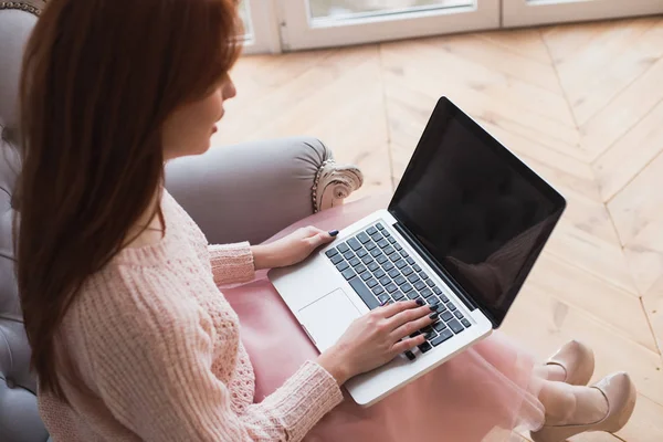 Une jolie jeune femme travaille sur son ordinateur portable. La fille cherche quelque chose dans Internet — Photo