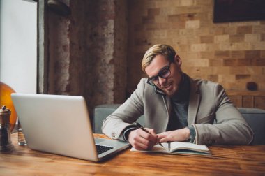 Gadget'ı kullanarak, kahve içme ve kafede çalışırken gülümseyen iş adamı