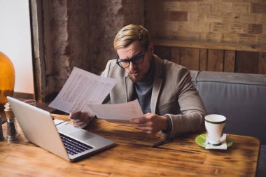 Genç işadamı tarafından tablo kafede otururken kağıtları arıyor