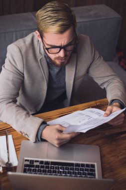 Genç işadamı tarafından tablo kafede otururken kağıtları arıyor