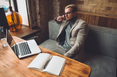 Bir kafede yakışıklı bir işadamı telefonda konuşuyor.