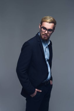 Şık ve kendinden emin. Gri arka plan önünde pantolon cebinde elele iş kişinin tam uzunlukta bir portre.