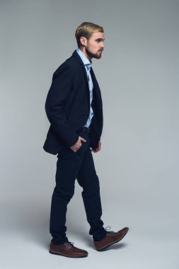 Hareket ve kavram. Yakışıklı iş adamı gri arka plan önünde adım an tam uzunlukta bir fotoğrafı.