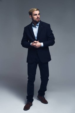 Kendinden emin ve profesyonel. İş adamı gri arka plan önünde şık kostüm tam uzunlukta bir portresi.