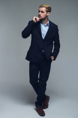 Yakışıklı ve profesyonel. Düşünme ve bir kenara izlerken önünde gri arka plan başarılı kişinin tam uzunlukta bir fotoğrafını.