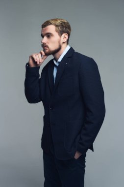 Yakışıklı ve acımasız. Çene gri duvar önünde el koyarak şık iş adamı profili.