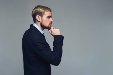 Yakışıklı ve acımasız. Çene gri duvar önünde el koyarak şık iş adamı profili.