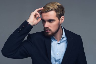 Şık ve acımasız. Onun saç modeli gri duvar önünde sabitleme yakışıklı iş adamı.