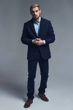 Kendinden emin ve profesyonel. İş adamı gri arka plan önünde şık kostüm tam uzunlukta bir portresi.