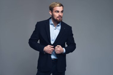 Profesyonel ve şık. Lapels ceketinin gri arka plan önünde tutan bir iş adamı portresi.