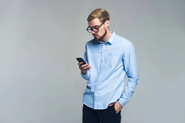 Serio y guapo. Joven hombre de negocios mensajería en su teléfono móvil. Fondo gris . —  Fotos de Stock