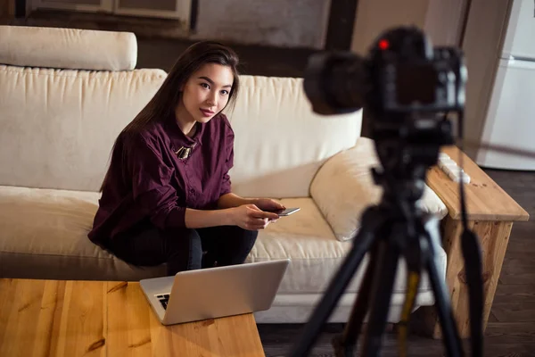 Красивая девушка сидит перед камерой и держать ее ежедневный видеоблог сидя на удобном диване дома . — стоковое фото