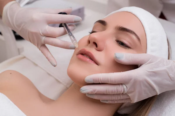 ¡Conserva tu belleza! Mujer joven acostada de placer obtiene inyecciones faciales de belleza en el salón de cosmetología . — Foto de Stock