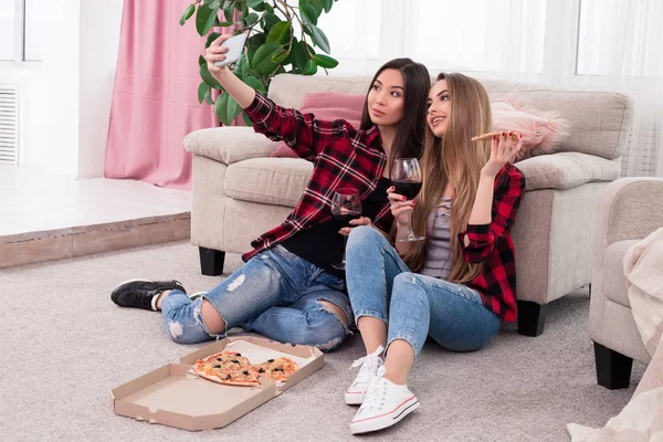 Zeit, Spaß zu haben! schön aussehende entzückende Schönheiten, die Bilder von sich machen, während sie auf dem Boden sitzen und wunderbare Freizeit in der Wohnung haben. — Stockfoto