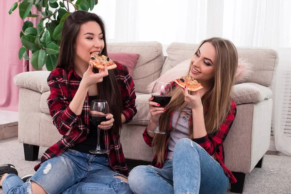 O melhor amigo está sempre por perto! Foto de close-up de jovens senhoras de boa aparência deliciosa degustação de queijo pizza italiana com vinho tinto . — Fotografia de Stock