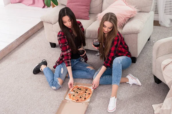 Bester Freund ist immer in der Nähe! zwei entspannte schöne Mädchen, die zu Hause Pizza essen, Wein trinken und über ihr Leben sprechen. — Stockfoto