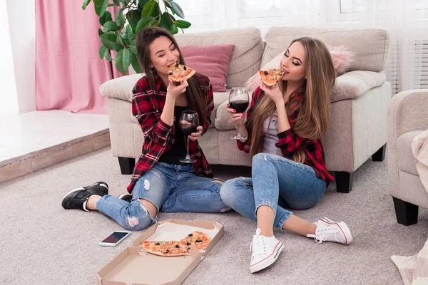 Através de amigos estadia grossa e fina para sempre! Relaxado atraente jovem sorridente senhoras beber vinho e comer pizza em casa . — Fotografia de Stock