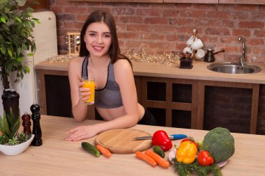 Sağlıklı bir gelecek şimdi başlıyor! Gülümseyen ve modern mutfağında lezzetli meyve suyu içme bir model olarak poz genç yakışıklı fitness kız.