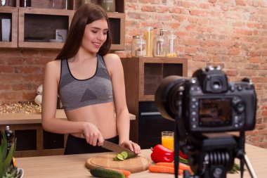 Sağlıklı bir beden sağlıklı yemek yiyor! Mutfakta yemek yaparken parçalar halinde salatalık Dilimleme büyük bir yapı ile çekici genç kadın.