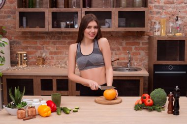 Bir yuh ver, daha fazla meyve yiyin! Greyfurt bir gülümseme ile kesme ve rahat mutfağını kamerada poz çekici çekici genç kız.