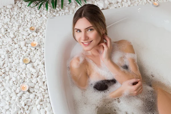 Save your youth! Smart gorgeous smiling young woman relaxing in round indoor bath with organic skin care in the luxury spa hotel.