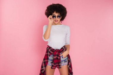 Eğilimleri olun! Güzel yakışıklı genç kız düz seyir ve pembe arka plan resim için poz güneş gözlüğü.