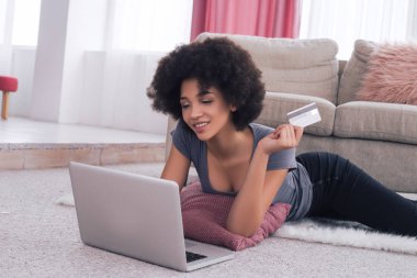 Online alışveriş kolay izin! Onu laptop yakın yerde yatan ve kredi kartı ile alışveriş zarif güzel bir genç kadın.