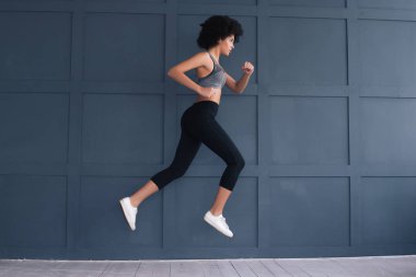 Şekil sizin yararınız için unutmayın! Havada çalışan ve sıkı spor kıyafetlerle muhteşem yakışıklı genç atlet kız.