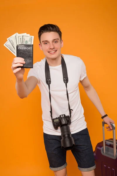 Die Welt ist voll von Reisenden! Nahaufnahme des lächelnden gutaussehenden jungen Mannes mit einem Fan von Bargeld und einer Kamera am Hals. — Stockfoto