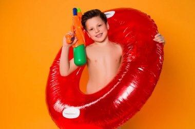 Oynamak bilmek mutlu bir yetenektir! Yakışıklı genç ve güzel çocuk taşıma kauçuk halka gülümseyen ve onun su tabancası ile oynarken.