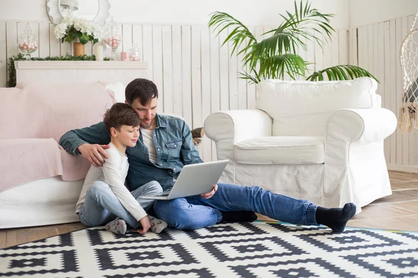 L'un des plus grands titres au monde est parent ! Père assis sur le tapis avec son petit fils et le tenant dans les bras, tout en regardant un film . — Photo