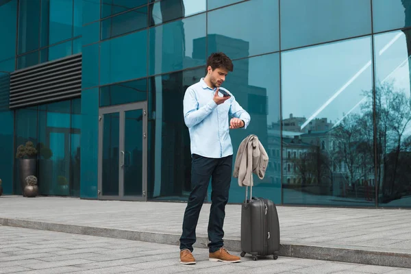 Un travail efficace ! Smart beau jeune homme en voyage d'affaires laissant un message vocal depuis son téléphone portable et debout près de l'aéroport . — Photo