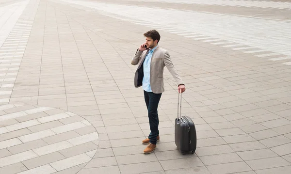 Réflexion stratégique ! Beau jeune homme d'affaires avec ses bagages debout et parlant au téléphone à l'aéroport, en attendant son départ . — Photo