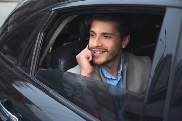 ¡Más cerca del éxito! Impresionante afortunado joven inteligente que tiene una conversación de negocios, mientras usa su teléfono inteligente y va en el coche en el camino al aeropuerto . — Foto de Stock