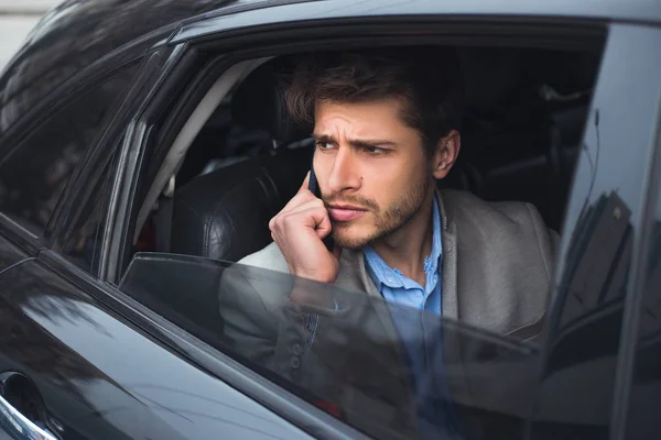 ¡Día de trabajo! Decisivo hombre guapo serio tener una charla de negocios, mientras usa su teléfono inteligente y va en el coche al aeropuerto . — Foto de Stock