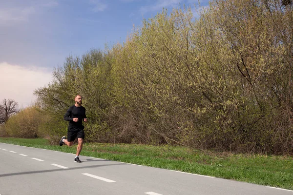 Lauf weit genug! Ganzkörperporträt des gut aussehenden, bärtigen Mannes, der an einem warmen Frühlingstag auf dem Sportplatz läuft. — Stockfoto