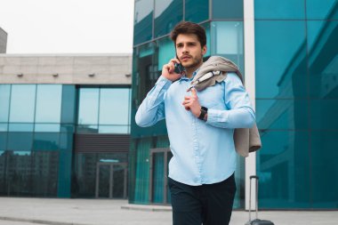 İş konuşuyor! Cidden akıllı telefon ve iş gezisinde uçan olacak konuşurken genç akıllı erkek profesyonel iş adamı.