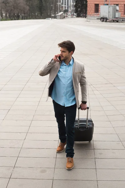 ¡Sólo avanzando! Inteligente viajero serio hombre de negocios con una maleta haciendo llamada telefónica e ir al viaje de negocios en el extranjero . — Foto de Stock