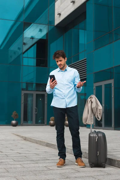 ¡Se acerca la decisión correcta! Guapo empresario inteligente en viaje de negocios en el extranjero mensajes de texto desde su teléfono celular, mientras que de pie al aire libre . — Foto de Stock