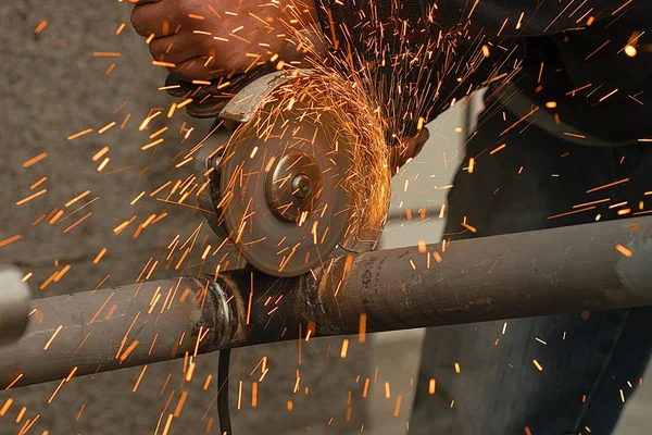 O funcionário corta um tubo metálico por meio da ferramenta abrasiva — Fotografia de Stock