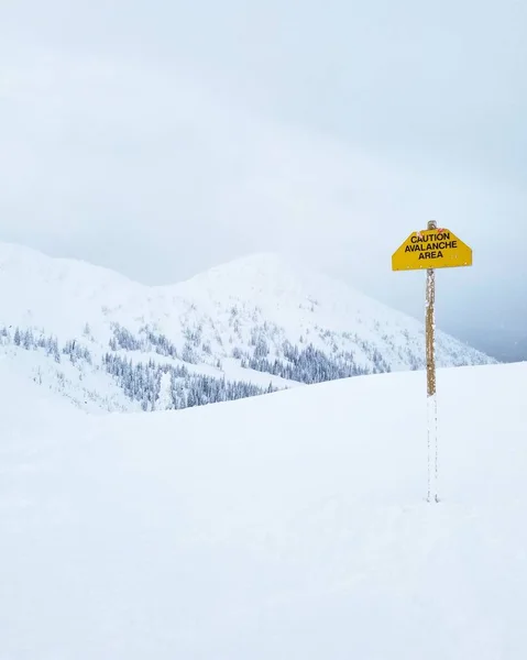 Sneeuw bedekt bergen met Avalanche Danger Sign Stockfoto
