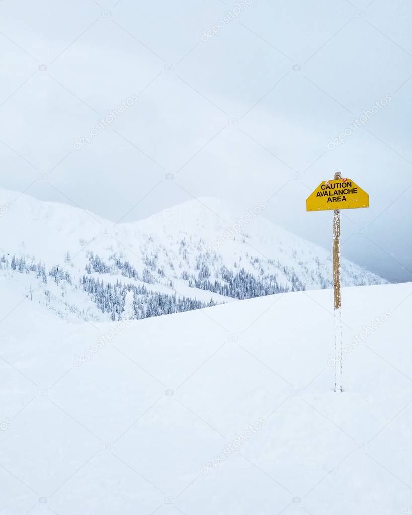 Snow Covered Mountains with Avalanche Danger Sign