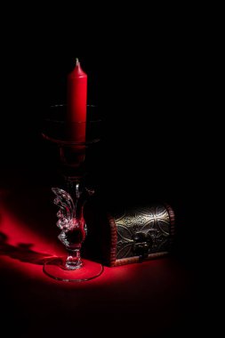 Cam kaplı, kırmızı mum ve küçük göğüslü şamdan.