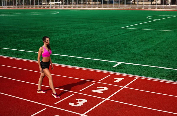 Athletic young woman at the sports track at the stadium is about to run a race at the running competition