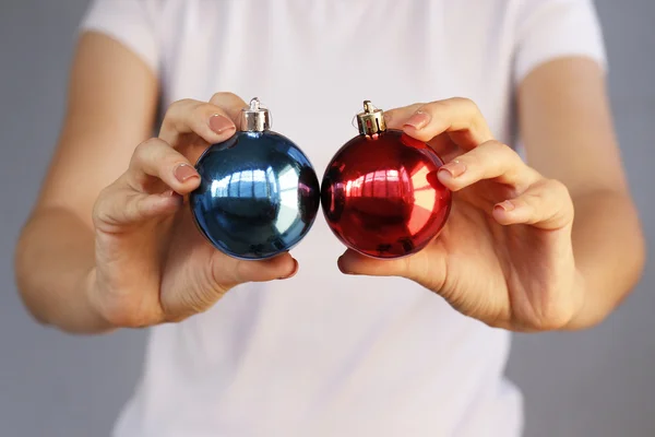 Meisje in wit t-shirt bedrijf Christmas speelgoed twee bal. Rood, blauw — Stockfoto
