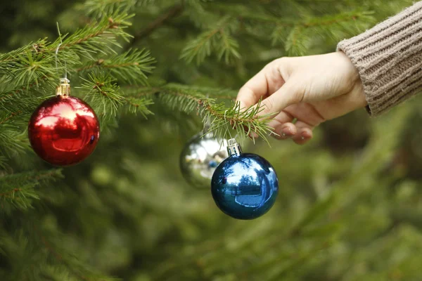 Meisje opknoping decoratieve speelgoed bal op kerstboom tak. — Stockfoto