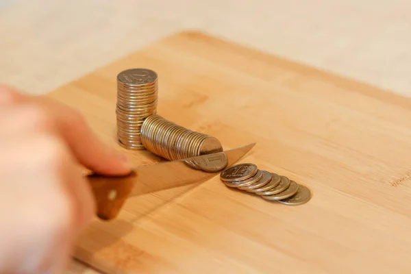 Mão com uma faca a cortar uma pilha de moedas. Conceito de cortes orçamentais — Fotografia de Stock
