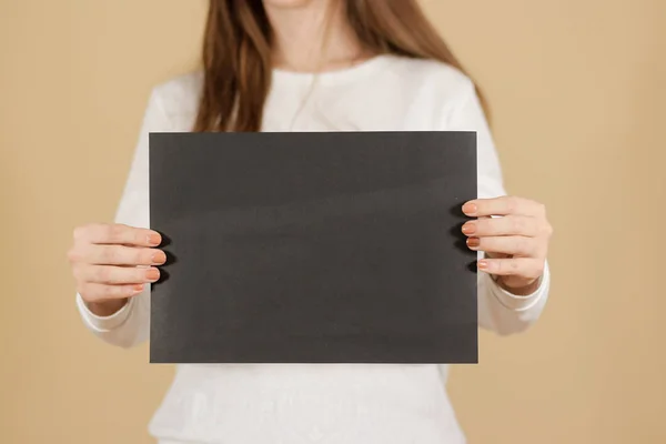 Chica sosteniendo papel en blanco A4 negro verticalmente. Folleto presentati — Foto de Stock