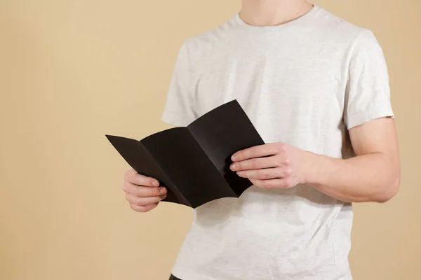 男人显示空白的黑色传单小册子。阅读详细的小册子。L — 图库照片