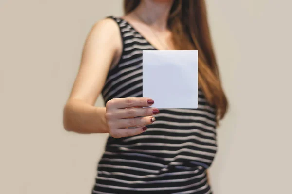 Девушка показывает брошюру с белыми квадратными листовками. Листовка — стоковое фото